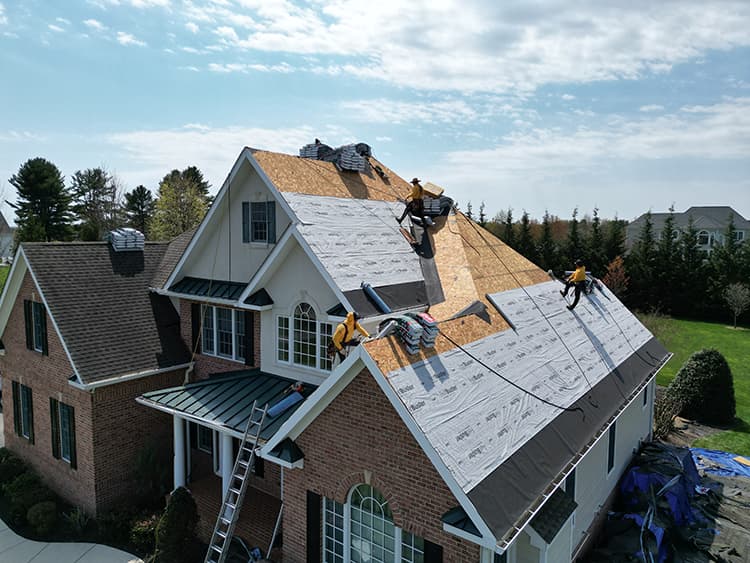 Roofing crew replacing the roof on a large home