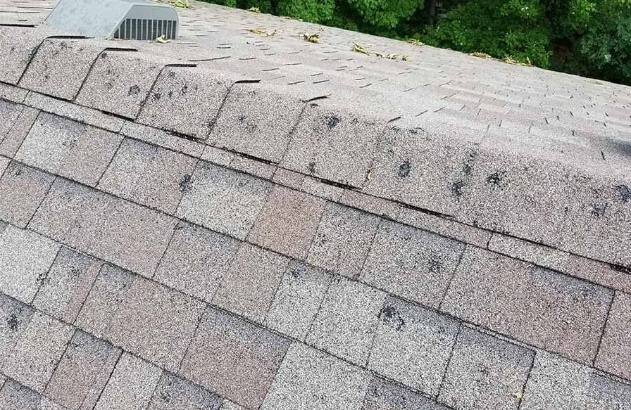 Hail impact damage across asphalt roof shingles