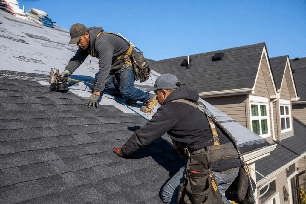 Roofing crew installing shingles on new residential construction
