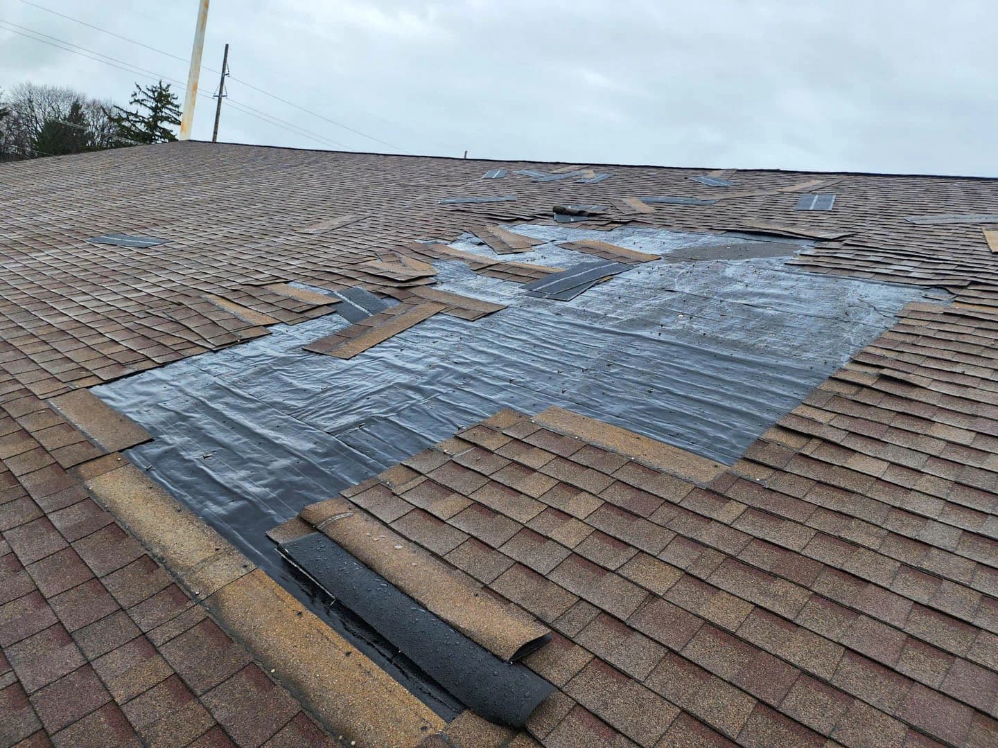 Temporary tarp installed over a storm-damaged roof